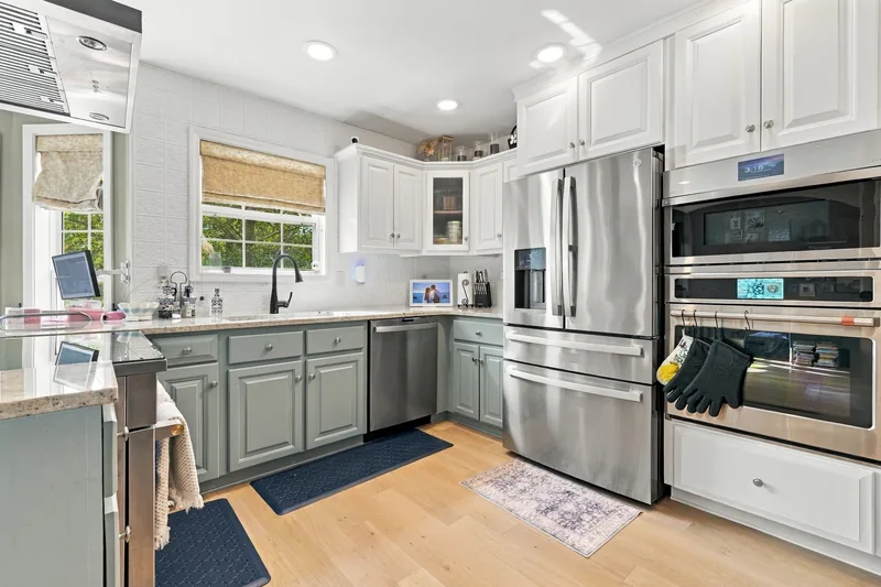 Kitchen with white and sage cabinets and stainless appliances